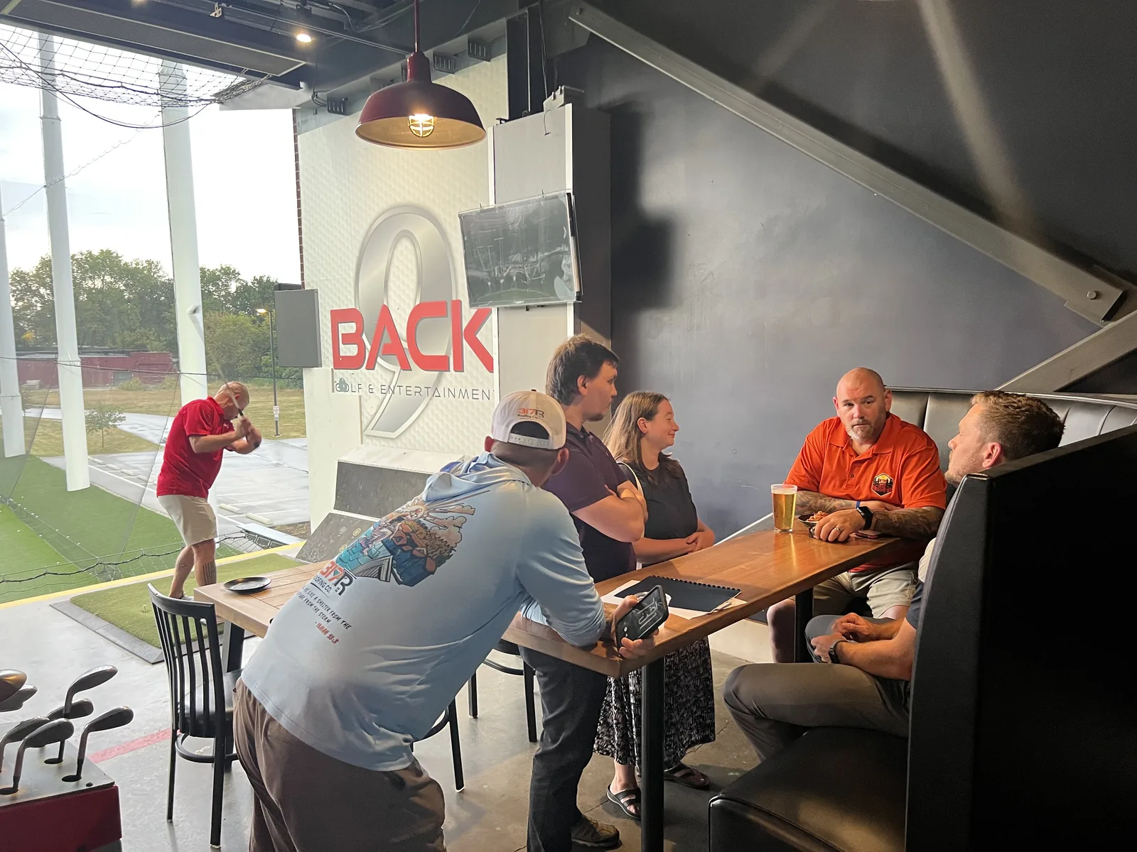 Business owners sharing a conversation beside a Back 9 golf bay