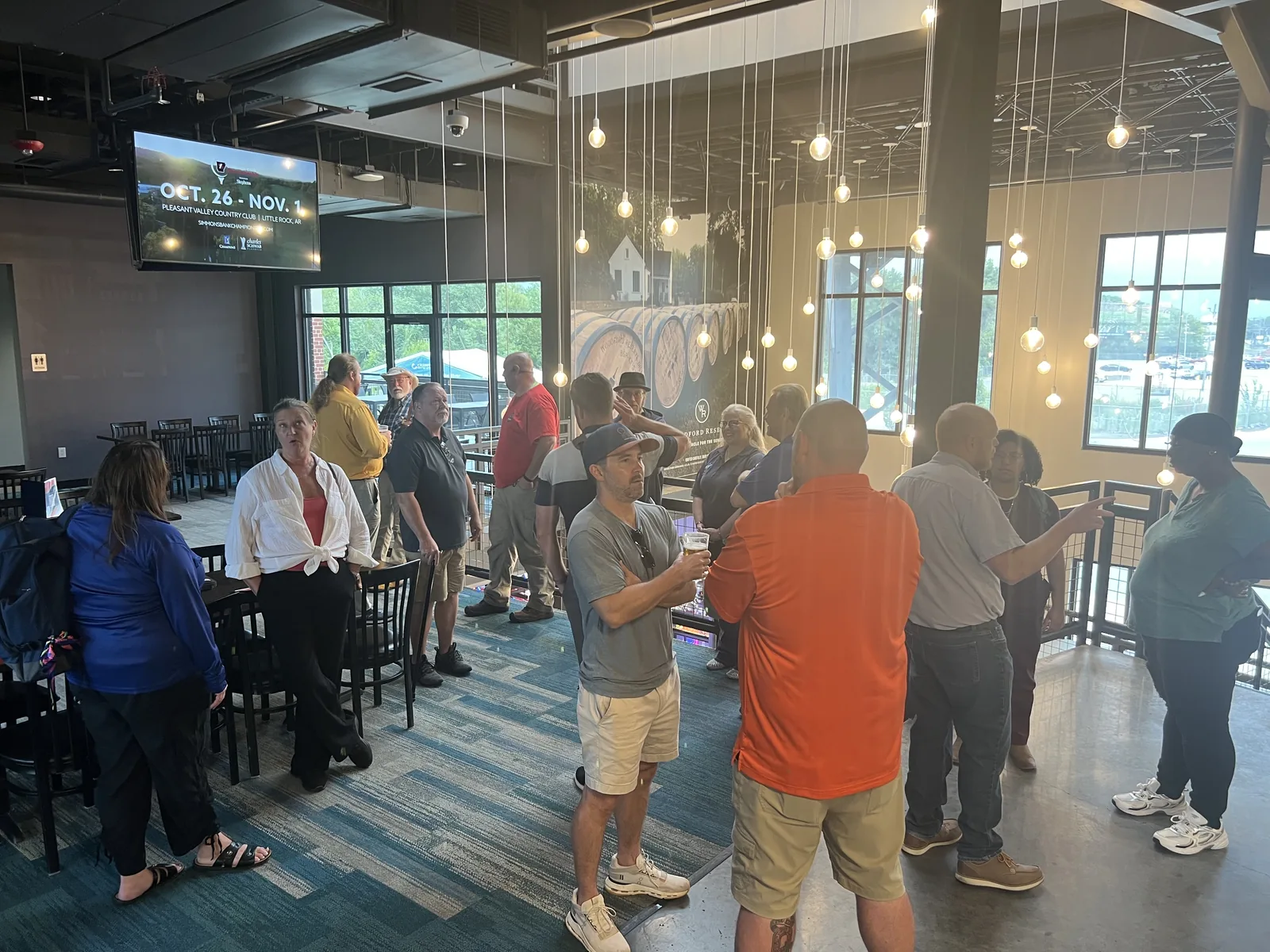 Networking on the Nines attendees talking in small groups beneath the lights at Back 9 Golf